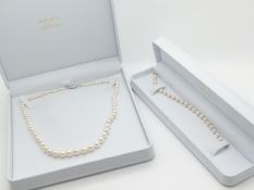 A single strand of pearls with a silver clasp and a pearl bracelet with alternating gold spheres