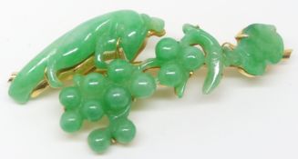 An 18ct gold brooch set with a carved jadeite section depicting animals, fruit and leaves by Zhou