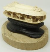 A 19thC Chinese carved ivory oyster shell containing an intricately carved village scene, mounted on