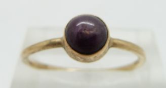 A gold ring set with a star ruby cabochon, size P