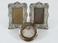 A pair of Edward VII hallmarked silver photograph frames with embossed decoration and easel backs,