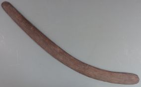A 19thC Australian Aboriginal boomerang or throwing stick with carved parallel lines and adzed