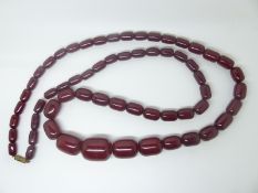 A large cherry amber necklace made up of graduated barrel shaped beads, 100g