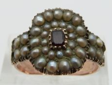 A Georgian rose gold ring set with seed pearls and a foiled garnet to the centre with original