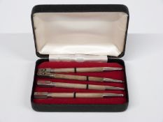 Cased set of four white metal propelling whist pencils, each with suit to top and marked sterling