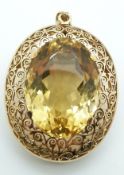 A 9ct gold pendant / brooch with scrolling and pierced border set with a 58ct citrine, with