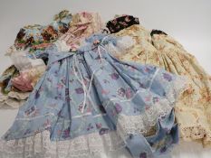 Five large dolls' dresses, four decorated with floral patterns and one with animal print.
