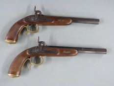 A pair of percussion hammer action pistols with chequered grip, ornate engraving to the locks,