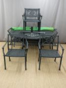 A cast aluminium garden table, diameter 152cm, with six chairs and cushions and matching umbrella