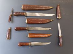 A set of five knives of graduated sizes. All in wooded sheaths. Largest 47cm, smallest 21cm.