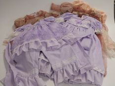 Five large dolls' dresses, all with floral and embroidered lace decoration.