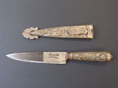 A knife in sheath impressed Tandril Argentina, with relief moulded decoration. Blade length 14cm.