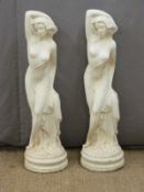A pair of garden statues of semi nude ladies with arms above their heads, height 85cm