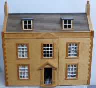 A three storey wooden dolls' house with two trays of wooden and metal furniture and accessories
