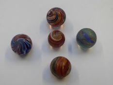 Five very large handmade glass marbles one with pink, blue and white central core surrounded by