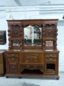 A late 19thC oak sideboard with bevelled edge mirror to back, carved columns and shelves, the base