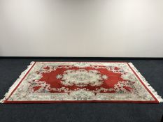A fringed embossed Chinese carpet on red ground,