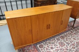 A teak shaped front four door sideboard