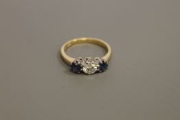 An 18ct gold three stone sapphire and diamond ring, the central stone weighing approximately 0.