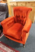 An Edwardian armchair in red/orange button fabric