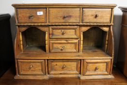 An antique pine wall cabinet fitted with eight drawers