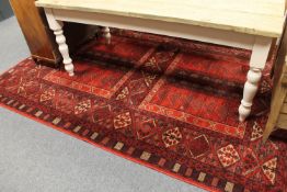 A machine made carpet of Ersari Ensi design, on red ground,