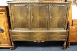 A twentieth century oak triple door sideboard fitted with six drawers