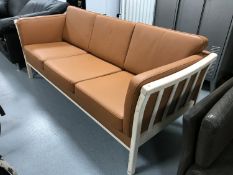 A pine framed three seater settee with tan leather cushions