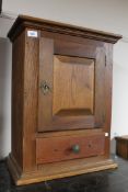 An antique oak hanging wall cabinet fitted with a drawer