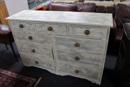A distressed pine nine drawer chest with knob handles