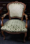 A carved walnut armchair upholstered in green brocade fabric