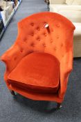 An Edwardian armchair in red/orange button fabric