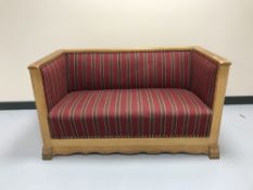 An oak framed hall settee upholstered in red striped fabric