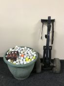 A tub containing a large quantity of golf balls together with a folding gold trolley