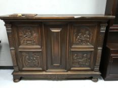 An early 20th century heavily carved oak sideboard on bun feet