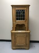 A blonde oak corner cabinet with stained leaded glass door