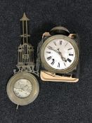 An early twentieth century metal wall clock with ornate pendulum and weights