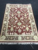 A fringed woollen Persian design rug on a red ground