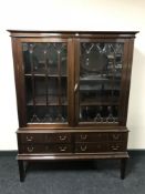 A mid twentieth century mahogany double door display cabinet fitted with four drawers beneath