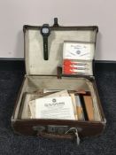 A vintage leather case containing ephemera, darts, monochrome photographs, miniature oil can,