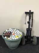 A tub containing a large quantity of golf balls together with a folding golf trolley