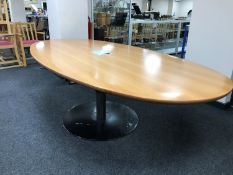 An oval beech boardroom table on circular metal base,
