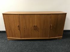 A teak shaped front four door sideboard