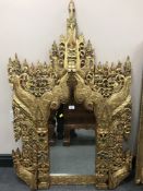 A carved Eastern gilded framed mirror embellished with coloured glass beads, width 87 cm.