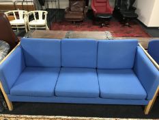 A continental contemporary beech framed three seater settee upholstered in blue fabric,
