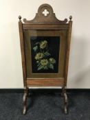 An early 20th century oak fire screen with floral panel,