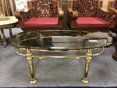 A mid 20th century oval brass coffee table with smoked glass top, 61 cm x 111 cm.