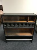 A mid 20th century cocktail cabinet, with glass sliding doors and graduated wine bottle holders,