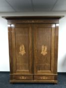 A continental inlaid mahogany double door panel wardrobe, fitted with two drawers,