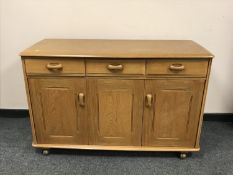 A light elm sideboard fitted with three drawers above cupboards, width 121 cm.
